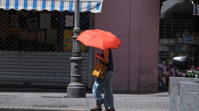 Una persona se protege del sol con un paraguas en una calle de Córdoba.