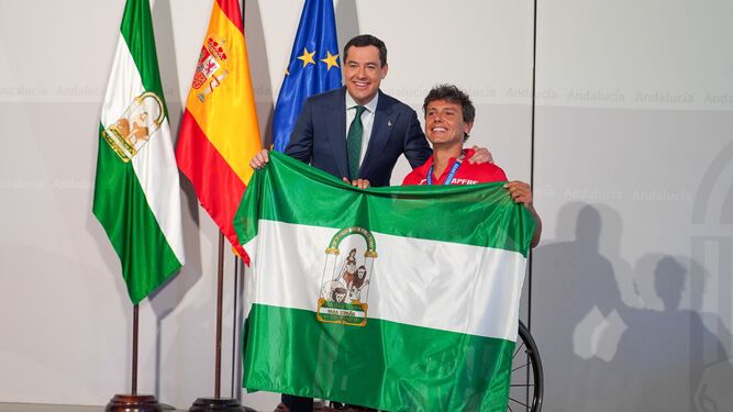 Cisco García posa sujeta la bandera de Andalucía junto a Juanma Moreno Bonilla.