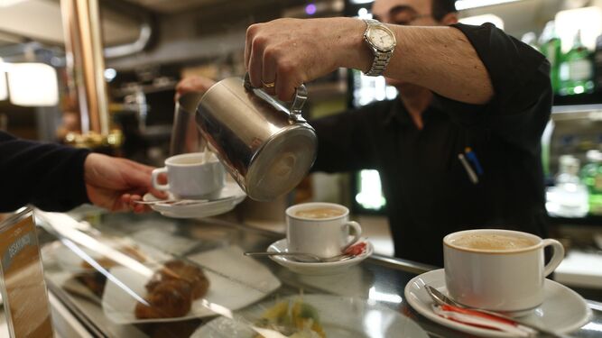 Un camarero sirve un café en un bar.