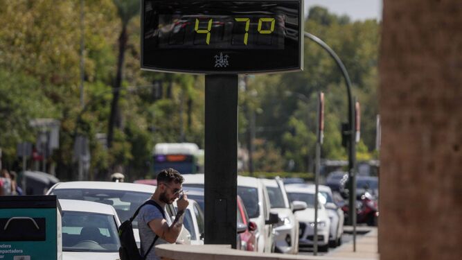 Un hombre pasa bajo un termómetro que registra una elevada temperatura en el centro de Córdoba.