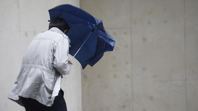 Un hombre se protege con un paraguas de la lluvia y el viento.