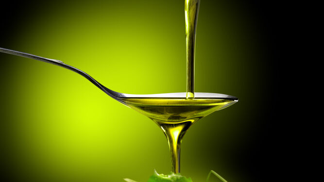 Un chorreón de aceite de oliva cae sobre unas hojas de lechuga.