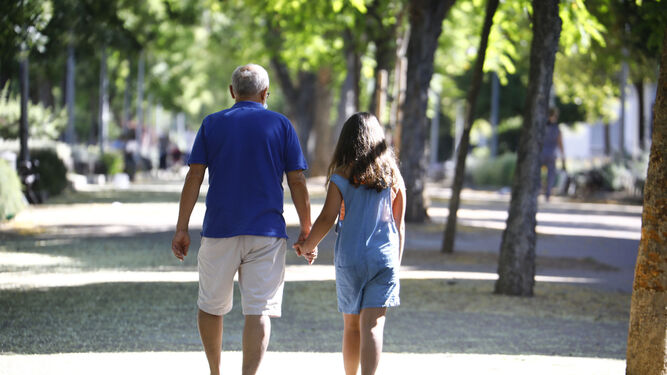 Un abuelo pasea con su nieta por una zona peatonal de Córdoba.