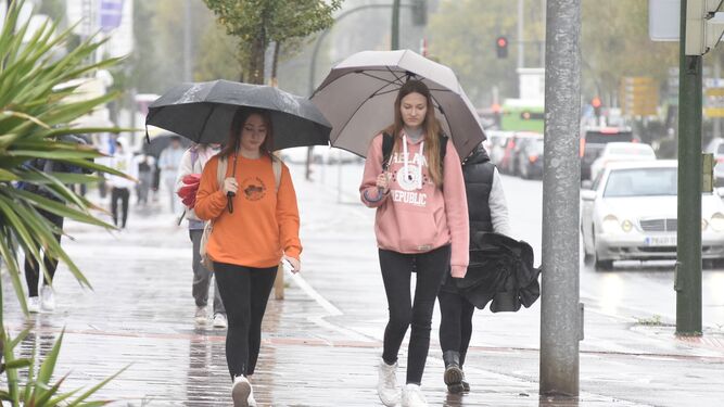 Dos jóvenes se protegen de la lluvia en Córdoba.
