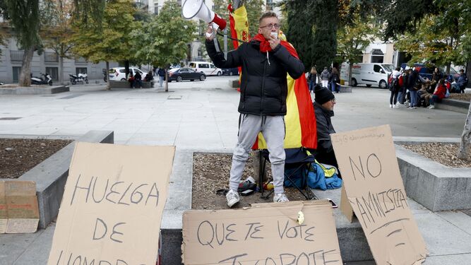Un joven se encadena ataviado con una bandera de España frente al Congreso contra la amnistía