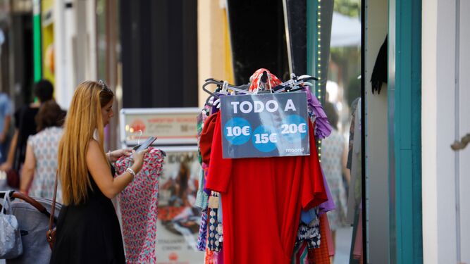 Una mujer mira la ropa de un perchero de un comercio de cercanía de Córdoba.