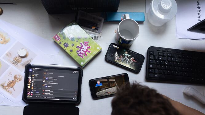 Varios dispositivos móviles  colocados sobre la mesa de un joven.