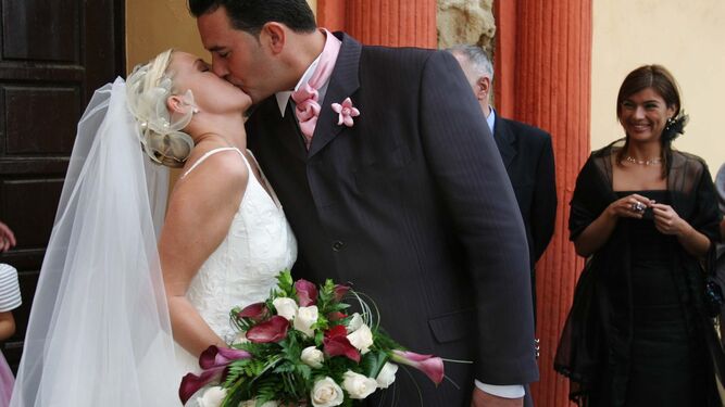 Una pareja ya casada se besa tras salir de la iglesia.