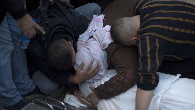 Familiares de un palestino muerto en un ataque israelí lloran junto a su cuerpo en el hospital Nasser de Jan Yunes.