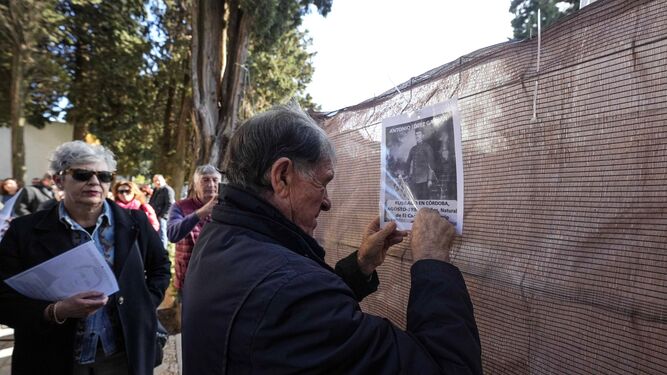 Un familiar de represaliados cuelga una fotografía en la valla de la fosa abierta en el cementerio de La Salud de Córdoba.
