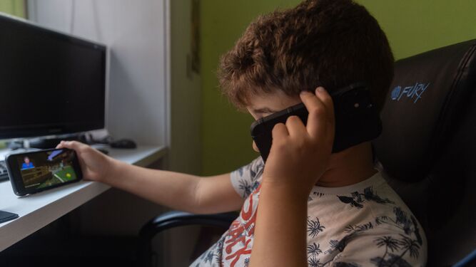 Un niño usa un móvil y una tablet.