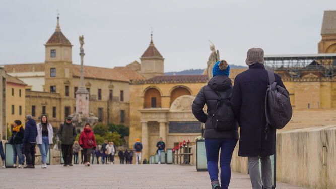 Viandantes pasando por el Puente Romano de Córdoba en una fría mañana.