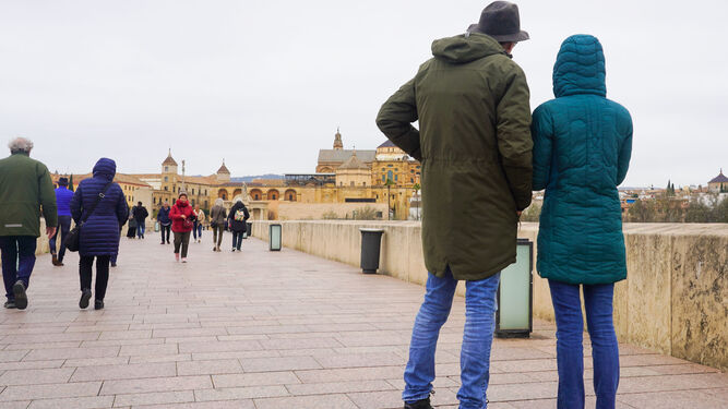 Turistas abrigados por el Puente Romano de Córdoba.