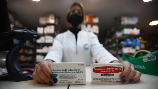Una farmacéutica muestra dos cajas de los medicamentos más vendidos para la gripe y el covid.