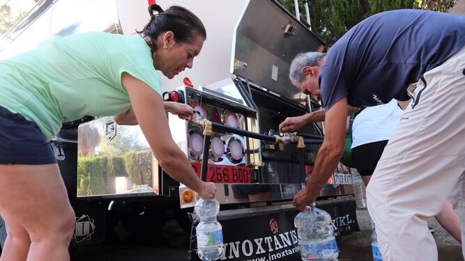 Vecinos de las Jaras llenan botellas de agua de un camión cisterna.