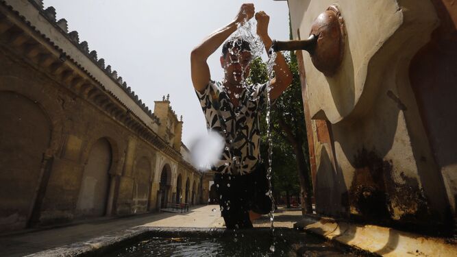 Un joven se refresca en una fuente de del Patio de los Naranjos de la Mezquita-Catedral de Córdoba.