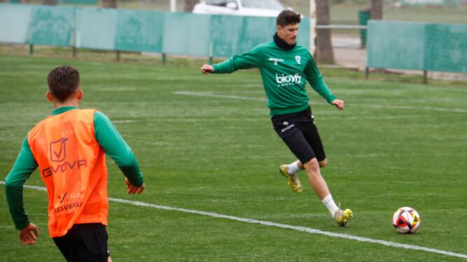 Carlos García golpea el balón en un entrenamiento del Córdoba CF, con Isma Ruiz de espaldas en la imagen.