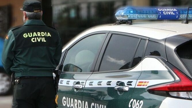 Un agente de la Guardia Civil, junto a un coche patrulla.