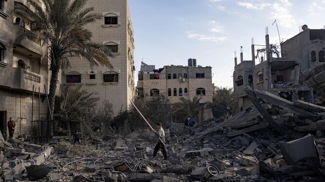Un palestino retira objetos entre los restos de una mezquita de Rafah.