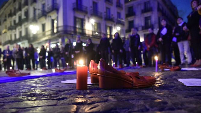 Una vela encendida y unos zapatos rojos, en una concentración contra la violencia de género.