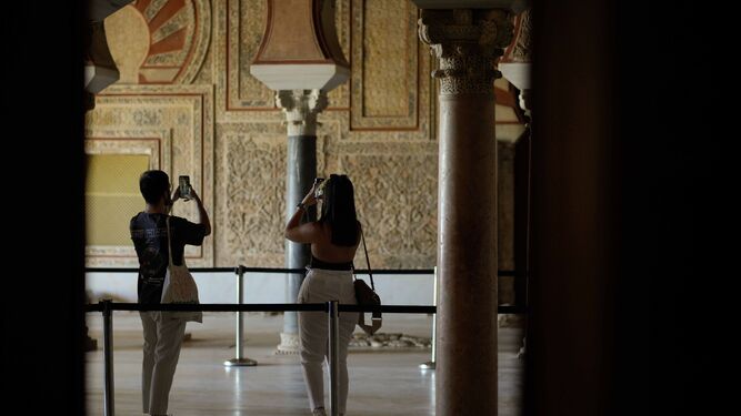 Dos personas toman fotos con su móvil en el Salón Rico de Medina Azahara.