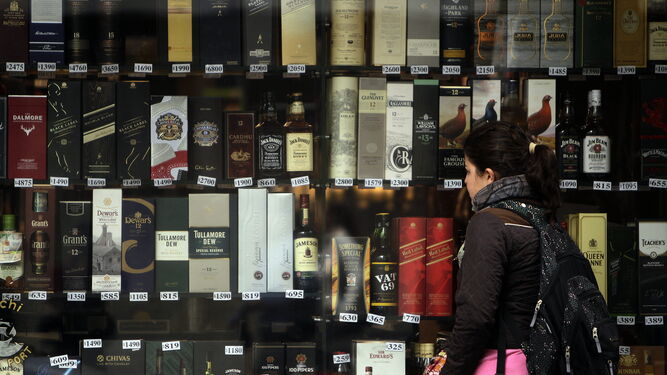 Una mujer observa botellas en una vitrina de una tienda de licores.