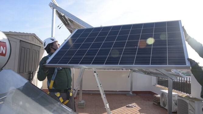Un operario instala una placa solar en el tejado de un edificio.