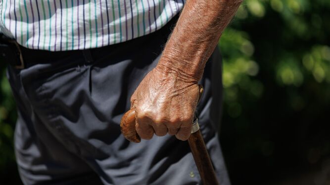 Un hombre mayor pasea apoyándose en un bastón.