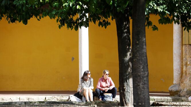 Dos mujeres descansan sentadas al sol en el Patio de los Naranjos de la Mezquita de Córdoba.