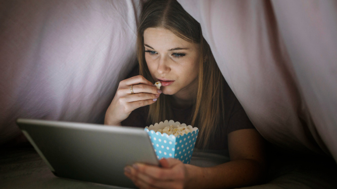 Mujer viendo una película y comiendo palomitas.