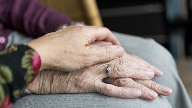 Una mujer posa sus manos sobre las de una persona mayor.