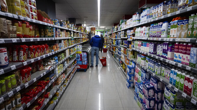 Varias personas hacen la compra en un supermercado.