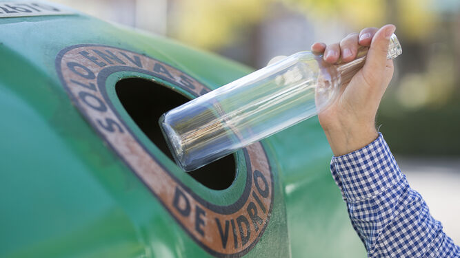 Una persona hace uso de un contenedor de envases de vidrio.