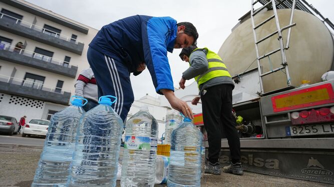 Varios vecinos recogen agua en garrafas desde los camiones cisterna.