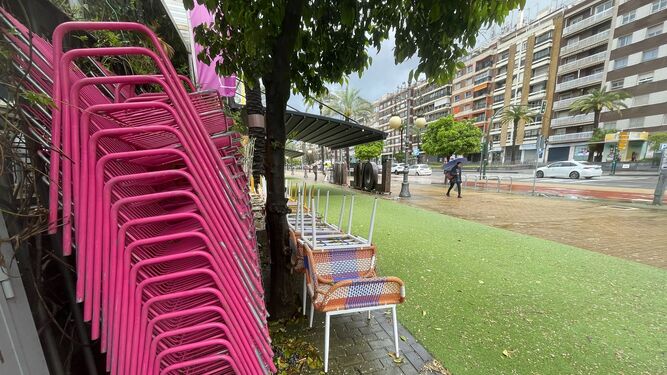 Sillas y mesas de una terraza de Córdoba recogidas por la lluvia.