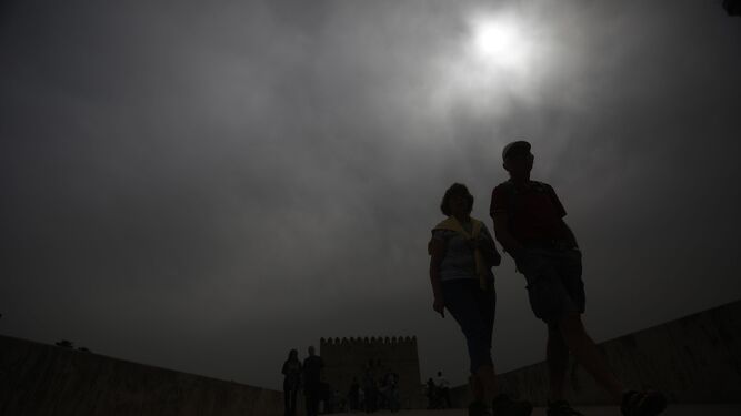 Varias personas pasean en Córdoba mientras el sol es tapado por la calima el pasado 23 de marzo.