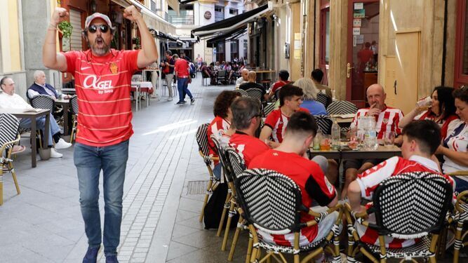 Un aficionado del Mallorca hace un gesto de júbilo junto a una mesa con seguidores del Athletic-.